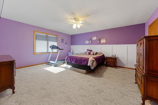 bedroom featuring a textured ceiling, ceiling fan, a wainscoted wall, and carpet