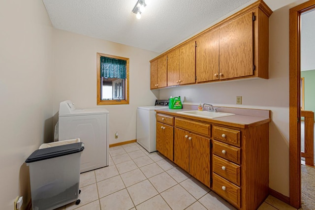 laundry area with washer and clothes dryer, cabinet space, light tile patterned flooring, a sink, and a textured ceiling