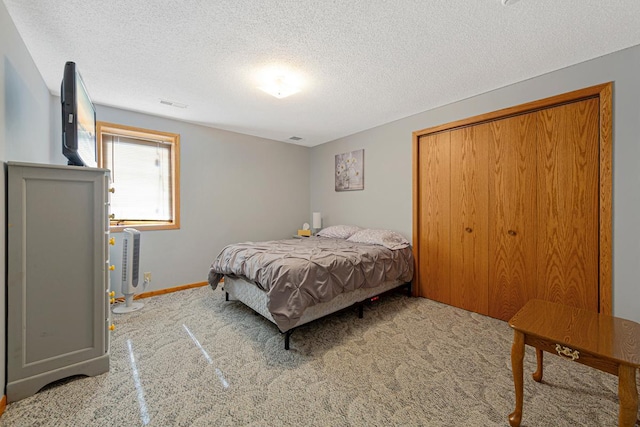 carpeted bedroom with a textured ceiling, a closet, visible vents, and baseboards