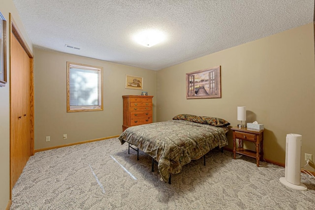 carpeted bedroom featuring a textured ceiling, visible vents, and baseboards