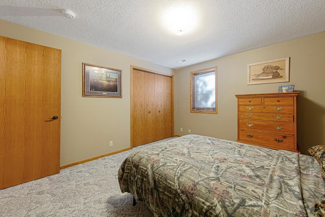 bedroom featuring a closet, carpet flooring, a textured ceiling, and baseboards