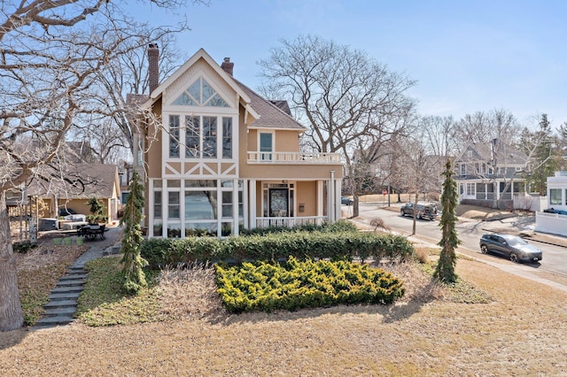 view of front of home featuring stucco siding, a balcony, a porch, and a chimney