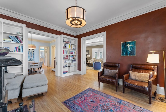 sitting room with a chandelier, baseboards, crown molding, and light wood-style floors