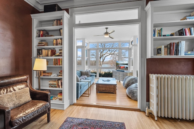 living area featuring radiator, a ceiling fan, and wood finished floors