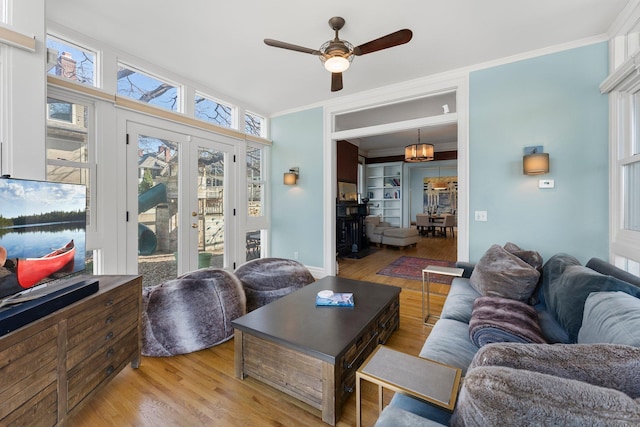 living area featuring wood finished floors, crown molding, built in shelves, and a ceiling fan