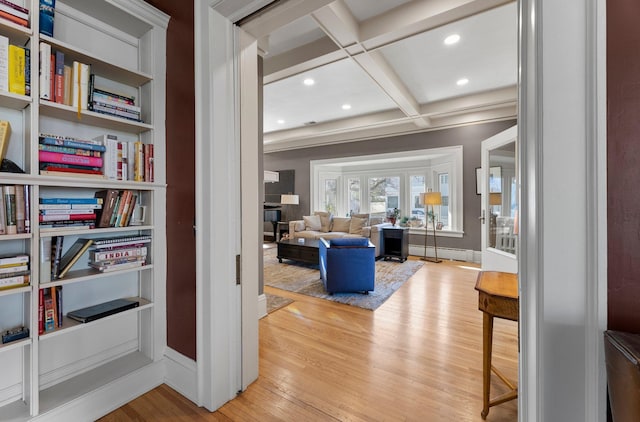 sitting room featuring a baseboard heating unit, beamed ceiling, wood finished floors, and baseboards