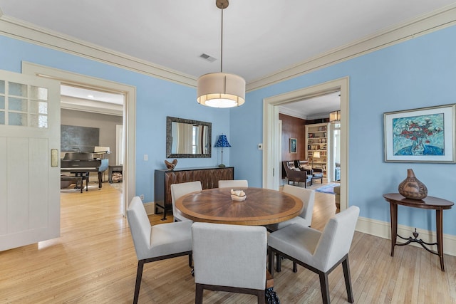 dining area featuring light wood-type flooring, visible vents, baseboards, and crown molding