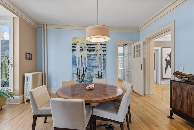 dining area featuring radiator heating unit, baseboards, light wood-type flooring, and ornamental molding