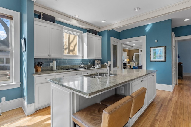 kitchen with a sink, a breakfast bar area, a healthy amount of sunlight, and an island with sink