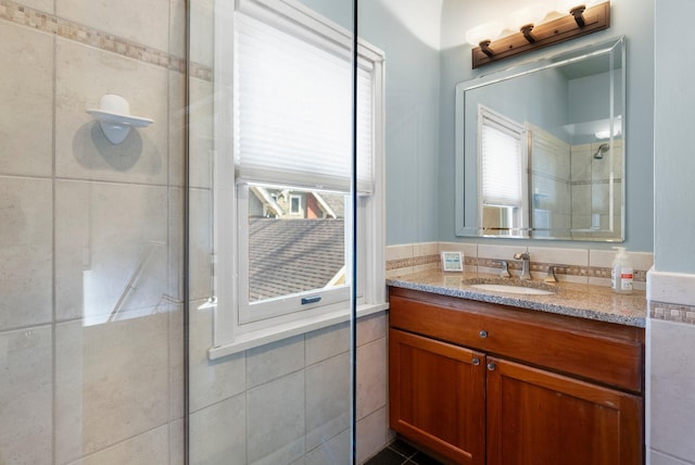 full bathroom with vanity, tiled shower, and tile walls