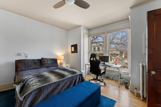 bedroom with ornamental molding, wood finished floors, radiator, baseboards, and ceiling fan