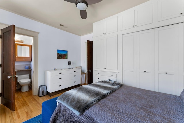 bedroom featuring visible vents, ensuite bath, ceiling fan, light wood-style floors, and a closet