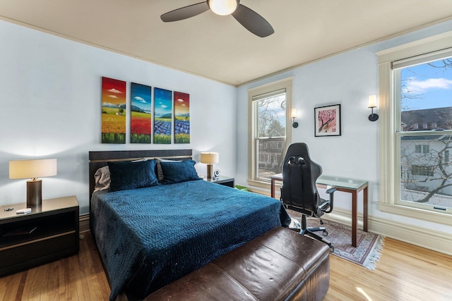 bedroom with a ceiling fan, wood finished floors, and baseboards