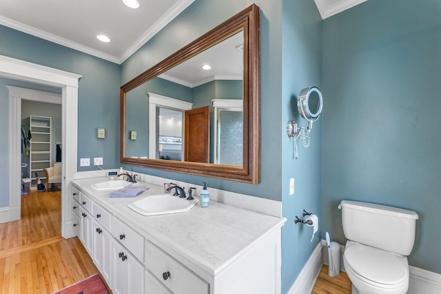 bathroom featuring wood finished floors, crown molding, and a sink