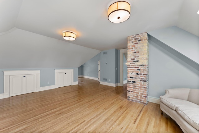 bonus room with lofted ceiling and light wood-style flooring