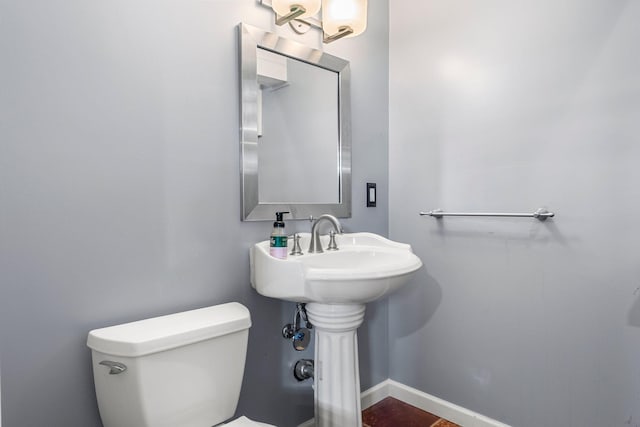 half bath featuring toilet and baseboards