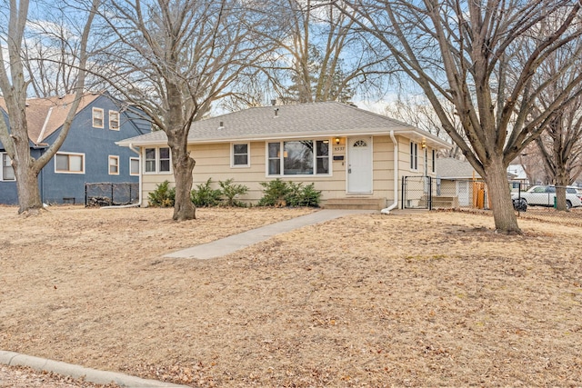 ranch-style home featuring roof with shingles and fence