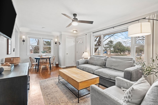 living area with a ceiling fan, light wood-style flooring, and baseboards