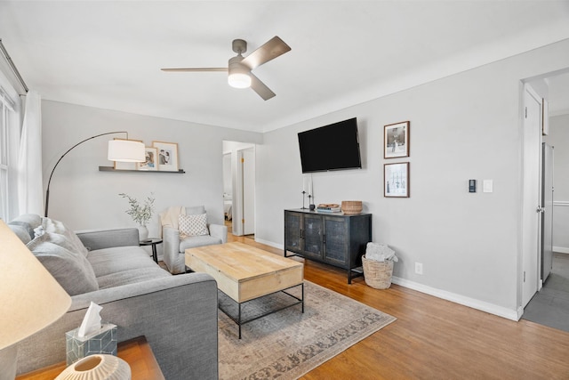 living room with a ceiling fan, baseboards, and wood finished floors