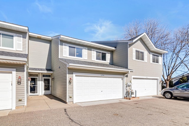 view of property featuring an attached garage and a shingled roof