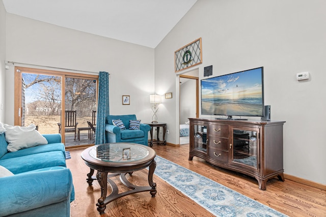 living room with baseboards, high vaulted ceiling, and wood finished floors