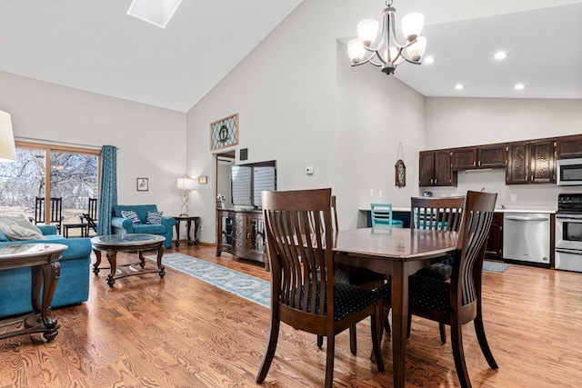 dining space with high vaulted ceiling, recessed lighting, light wood finished floors, and a chandelier