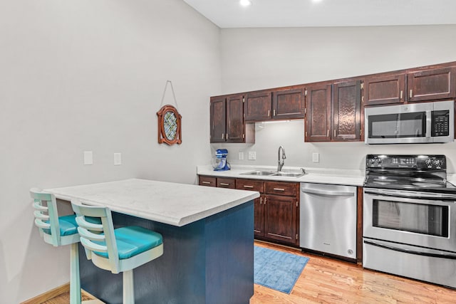 kitchen featuring a sink, light countertops, dark brown cabinetry, appliances with stainless steel finishes, and light wood-type flooring