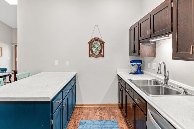 kitchen with light wood finished floors, a peninsula, a sink, light countertops, and dishwasher