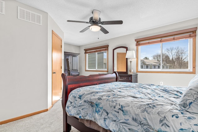 carpeted bedroom featuring visible vents, a textured ceiling, baseboards, and a ceiling fan