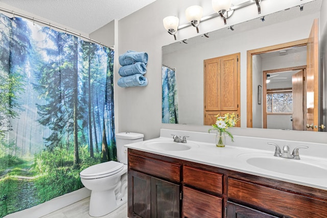 full bathroom featuring a textured ceiling, double vanity, toilet, and a sink