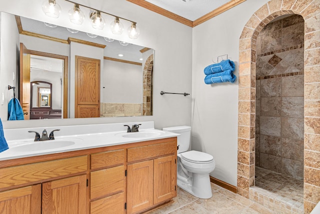 bathroom featuring tiled shower, toilet, crown molding, and a sink