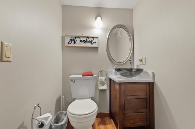 half bathroom with vanity, toilet, and wood finished floors