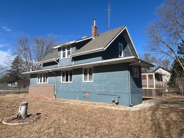 view of side of property with a shingled roof and a chimney