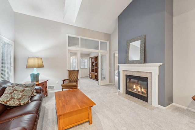 living room featuring a healthy amount of sunlight, a fireplace, high vaulted ceiling, and carpet flooring