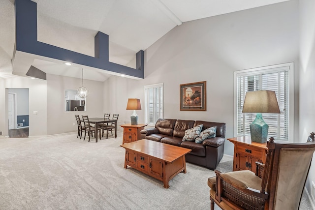 living room featuring beam ceiling, an inviting chandelier, light carpet, high vaulted ceiling, and baseboards