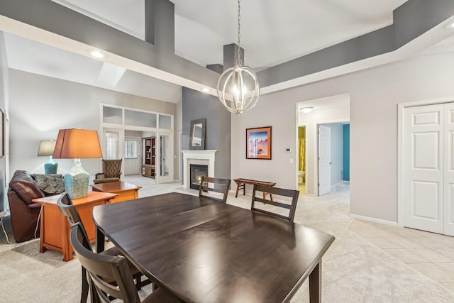 dining room featuring light tile patterned floors, a fireplace with flush hearth, light carpet, a chandelier, and baseboards