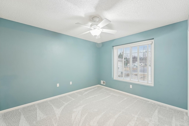 spare room featuring carpet, visible vents, a ceiling fan, a textured ceiling, and baseboards