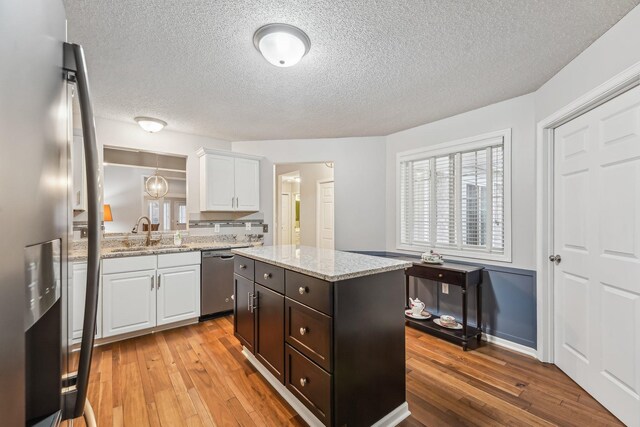 kitchen featuring stainless steel appliances, light wood-type flooring, a sink, and white cabinets