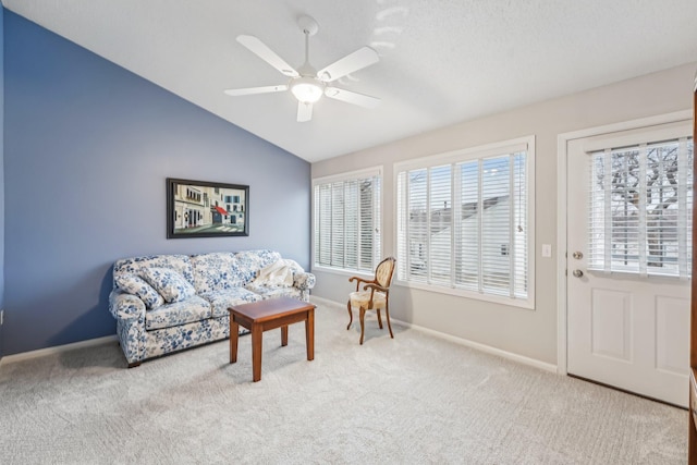 living room with ceiling fan, carpet, baseboards, and vaulted ceiling