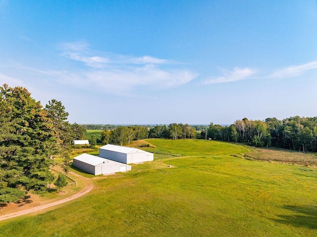 entry to storm shelter with a yard, a rural view, a pole building, and an outbuilding