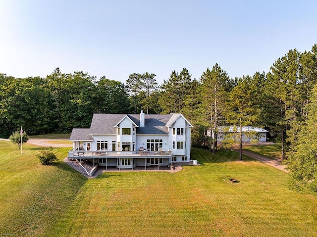 back of house featuring a lawn, a chimney, and a wooden deck