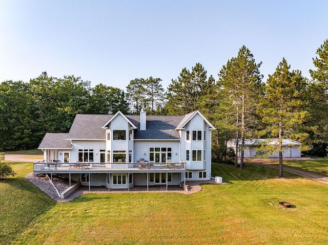 back of property with a deck, a yard, a shingled roof, and a chimney