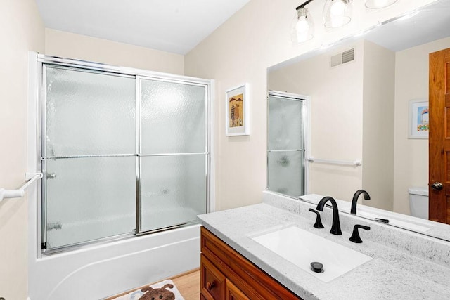 full bathroom with enclosed tub / shower combo, visible vents, vanity, and toilet