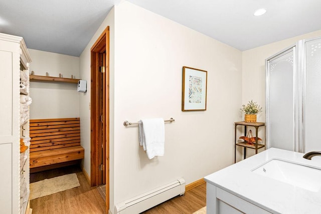 bathroom featuring recessed lighting, baseboard heating, a sink, wood finished floors, and baseboards