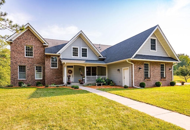 view of front of home featuring covered porch, brick siding, and a front yard