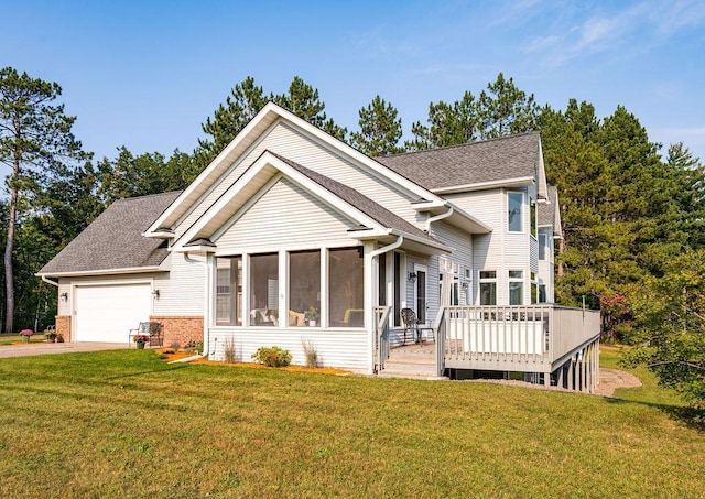 view of front of property with concrete driveway, a sunroom, an attached garage, a deck, and a front lawn