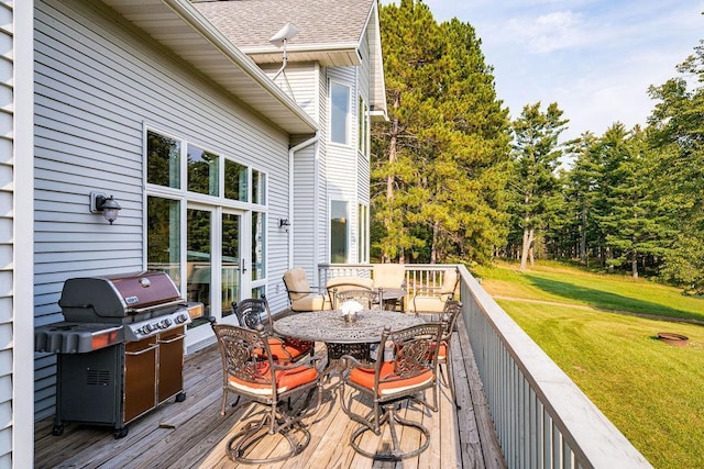 wooden terrace featuring outdoor dining area, a lawn, and a grill