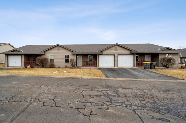 single story home with an attached garage, covered porch, and aphalt driveway