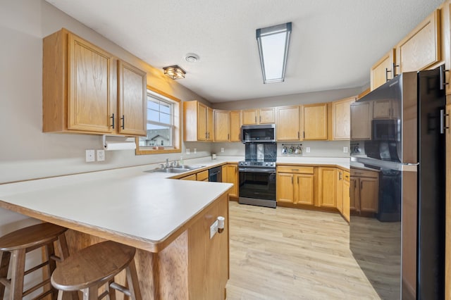 kitchen with light brown cabinets, stainless steel appliances, a peninsula, and light countertops