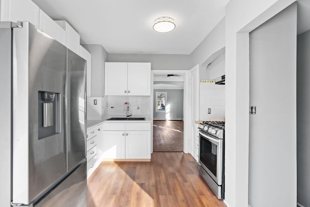 kitchen featuring tasteful backsplash, appliances with stainless steel finishes, white cabinets, and a sink